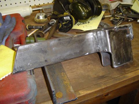 1989 Ford Bronco - A fabricated metal component sits on a workbench, surrounded by various tools and hardware.