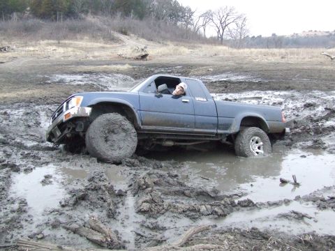 1986 Ford Bronco - A driver is stuck in a muddy field with their pickup truck submerged up to the doors.