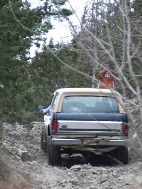 1986 Ford Bronco - A Ford Bronco navigates a rough, rocky path with a person standing on its roof.
