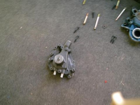 1986 Ford Bronco - A disassembled transfer case and associated parts are laid out on a carpeted floor, suggesting a motor swap or repair.