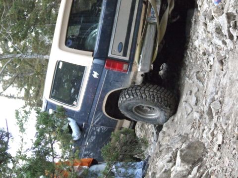 1986 Ford Bronco - This Ford Bronco is shown off-roading on a rocky terrain, with its tire positioned on a large rock.