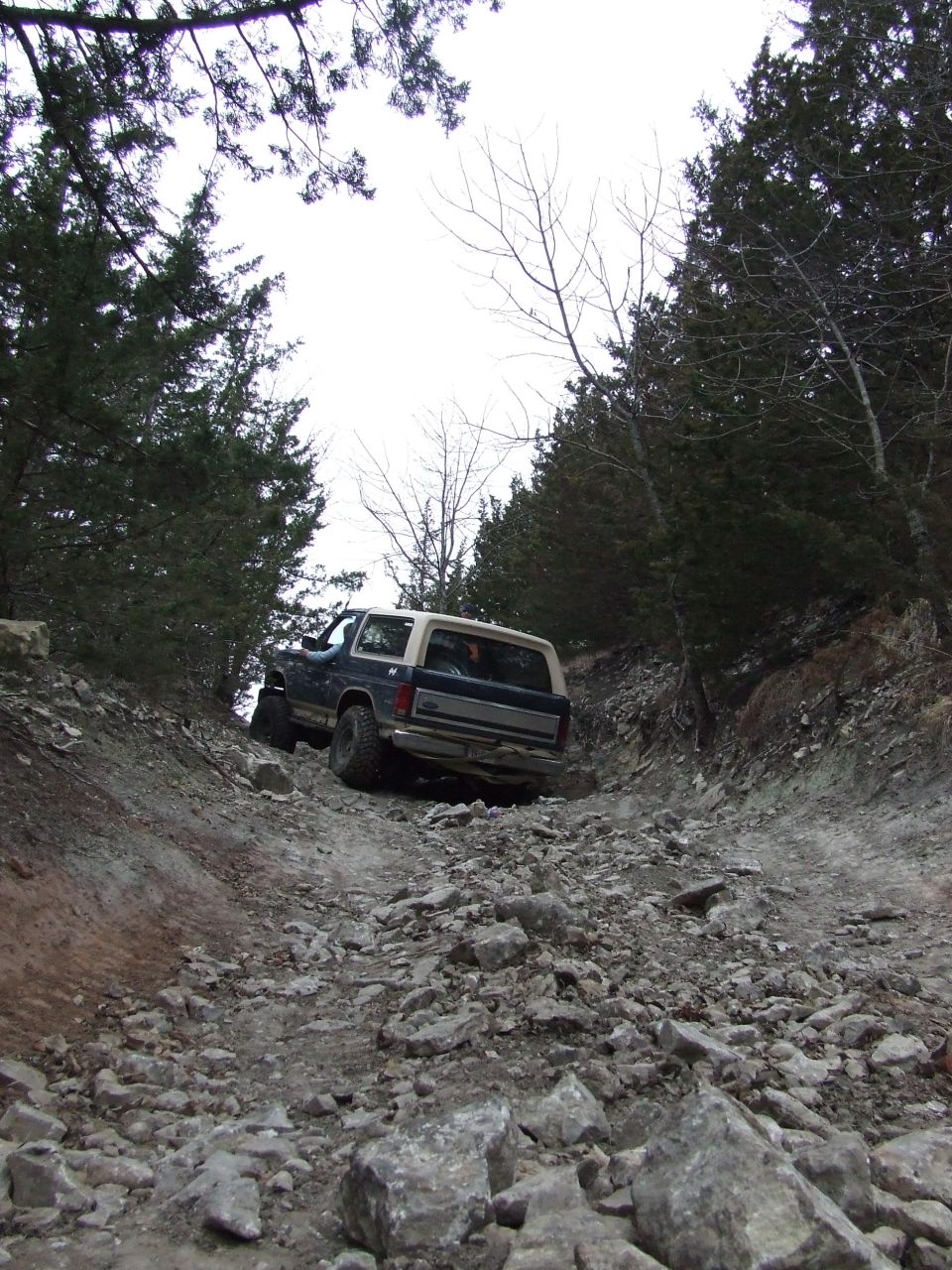 Rear view of a 1986 Ford Bronco climbing a rocky trail