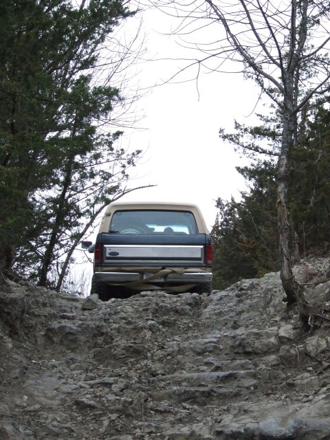 1986 Ford Bronco - A Ford Bronco navigates a challenging rocky terrain from a rear perspective.