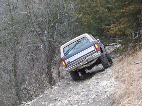 1986 Ford Bronco - This 1986 Ford Bronco navigates a challenging off-road path through a wooded area.