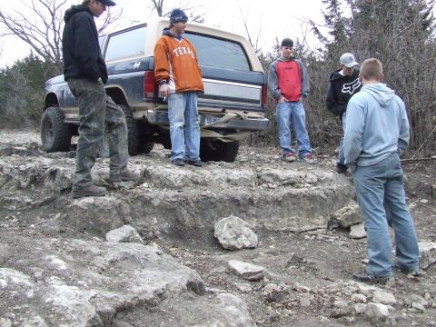 1986 Ford Bronco - A group of people stand around a 1986 Ford Bronco on a rocky trail.