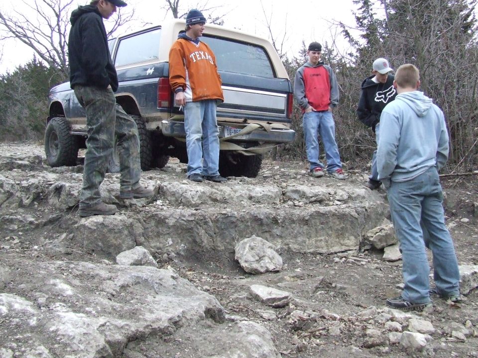 1986 Ford Bronco rear view with people standing around it on rocky terrain