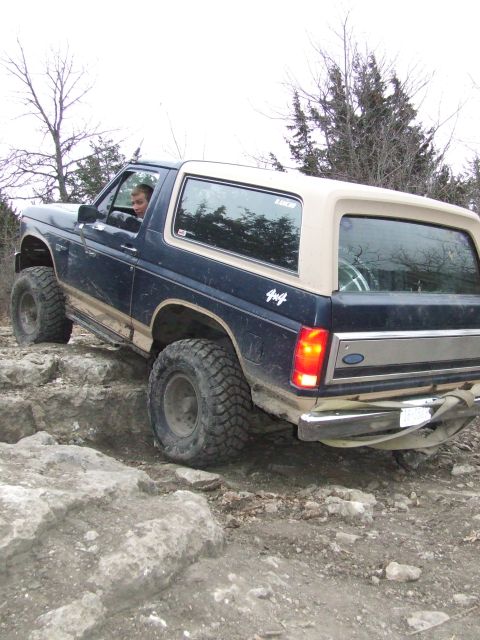 1986 Ford Bronco - Ford Bronco tackling a challenging off-road course with large rocks.