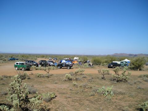 1993 Ford Bronco - A 1993 Ford Bronco is seen at a desert campsite alongside other vehicles and tents under a clear blue sky.