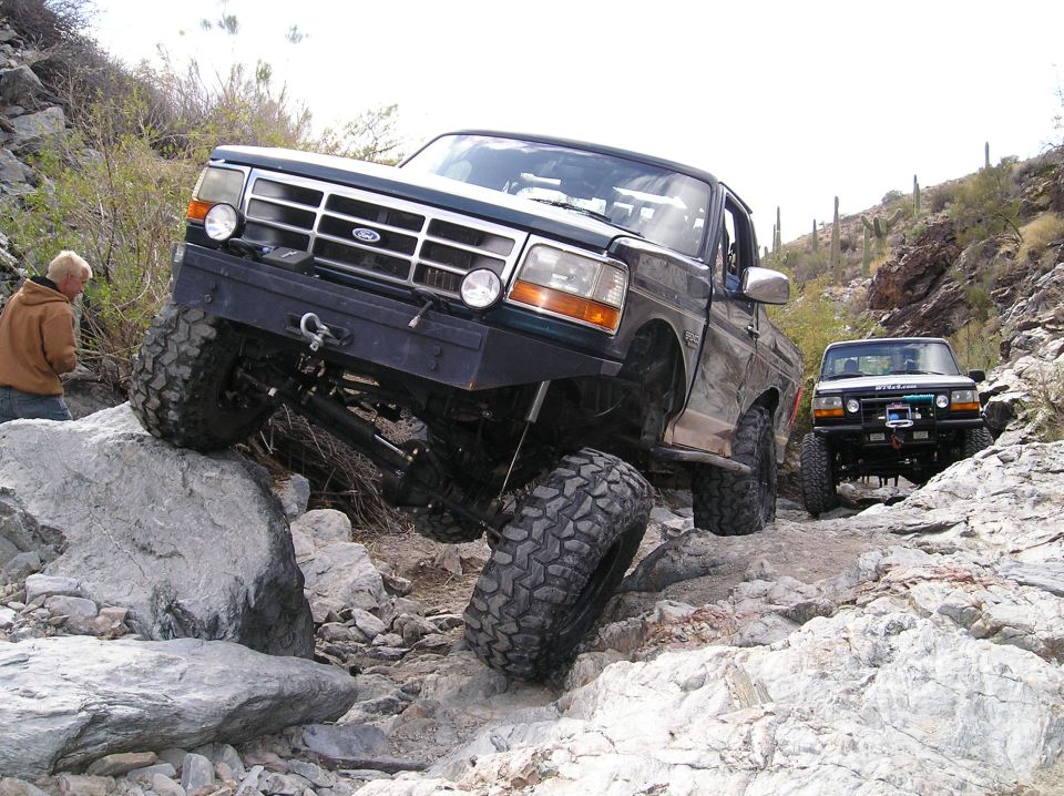 Ford Bronco going over rocks off-road. Another Bronco follows behind
