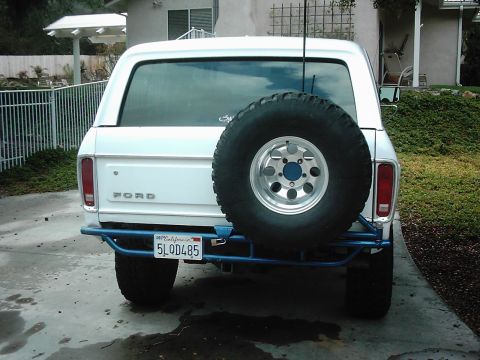 1978 Ford Bronco - Rear view of a white 1978 Ford Bronco, equipped with a spare tire and a blue custom bumper.