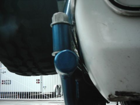 1978 Ford Bronco - Detail of a spare tire carrier mount, likely from an older vehicle, with trailers in the background.