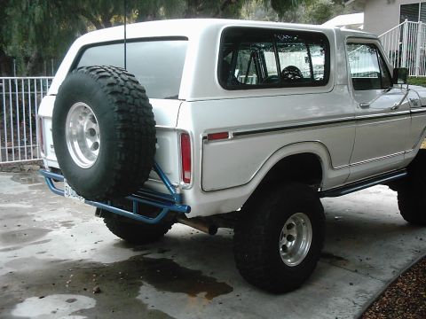 1978 Ford Bronco - Rear view of a white 1978 Ford Bronco, showing its spare tire carrier and lifted suspension.