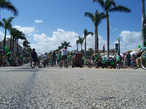 1994 Ford Probe - A parade is underway with participants on bicycles and in a wheelchair, under a bright blue sky.