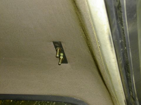 1993 Ford Bronco - Close-up inside a vehicle's tan headliner showing a small welded steel backing plate with two zinc-plated bolts protruding through the fabr…