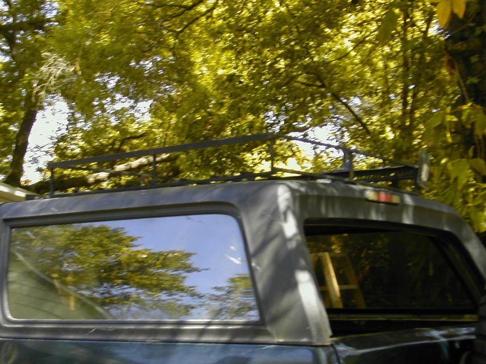 Welded steel roof rack on hardtop of dark green SUV under trees