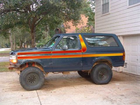 1993 Ford Bronco - This Ford Bronco is parked in front of a garage with trees in the background.