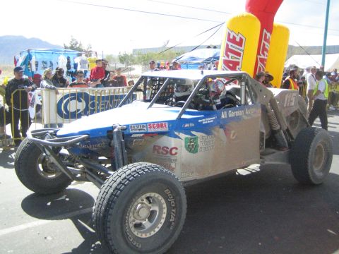 1990 Ford Bronco - blue and silver tube-frame off-road race buggy marked number 1118 sits at the start line beside a yellow Tecate inflatable.