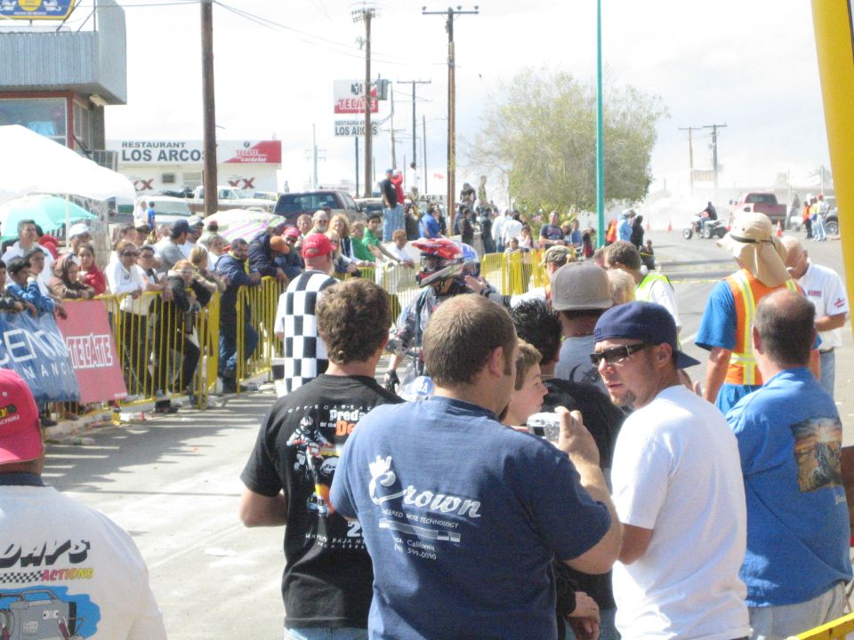 Crowd of spectators in T-shirts watching a roadside off-road race