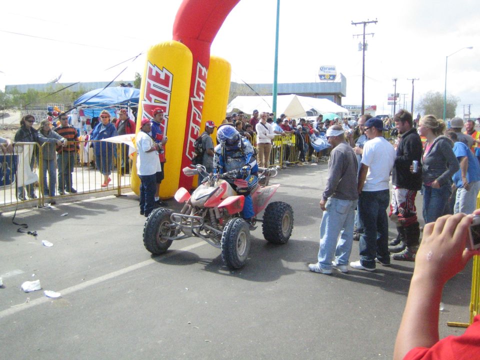 Red Honda ATV racer riding under a yellow Tecate arch