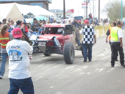 Red off-road race buggy beside an official waving a checkered flag