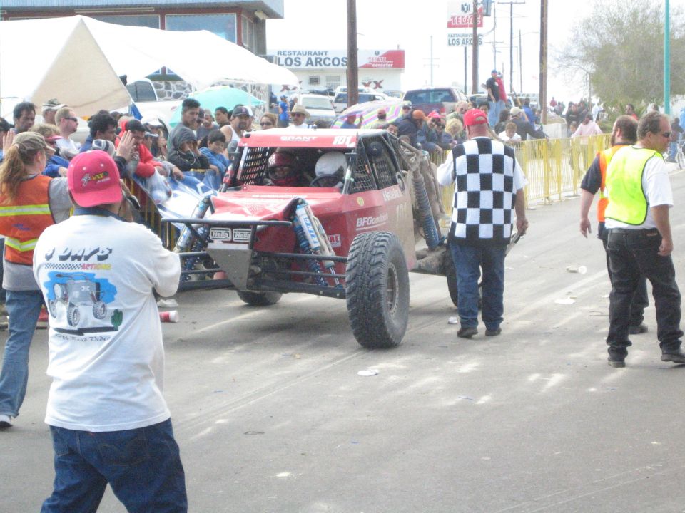 Red off-road race buggy beside an official waving a checkered flag