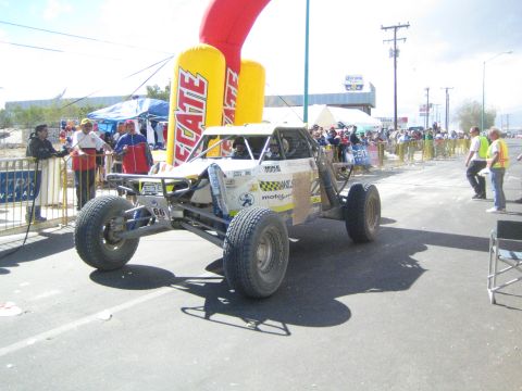 White open tube-frame off-road race buggy under a Tecate arch