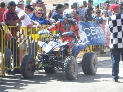 Blue and orange ATV quad racer between yellow barricades
