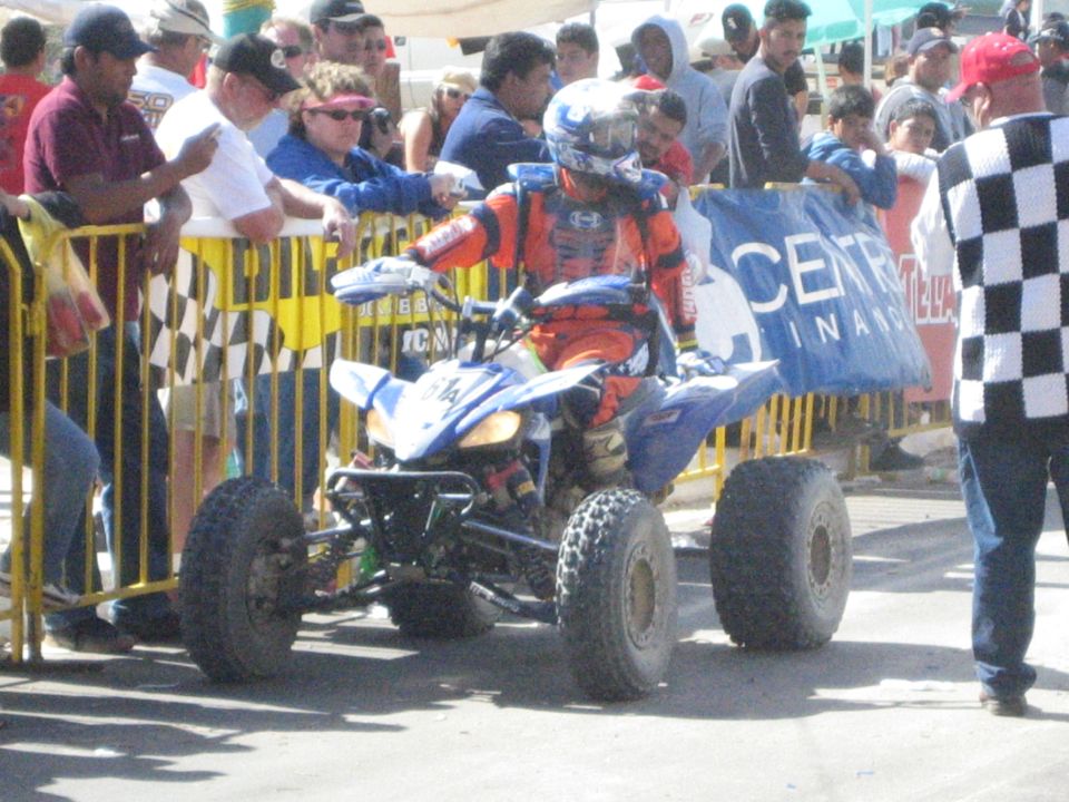 Blue and orange ATV quad racer between yellow barricades