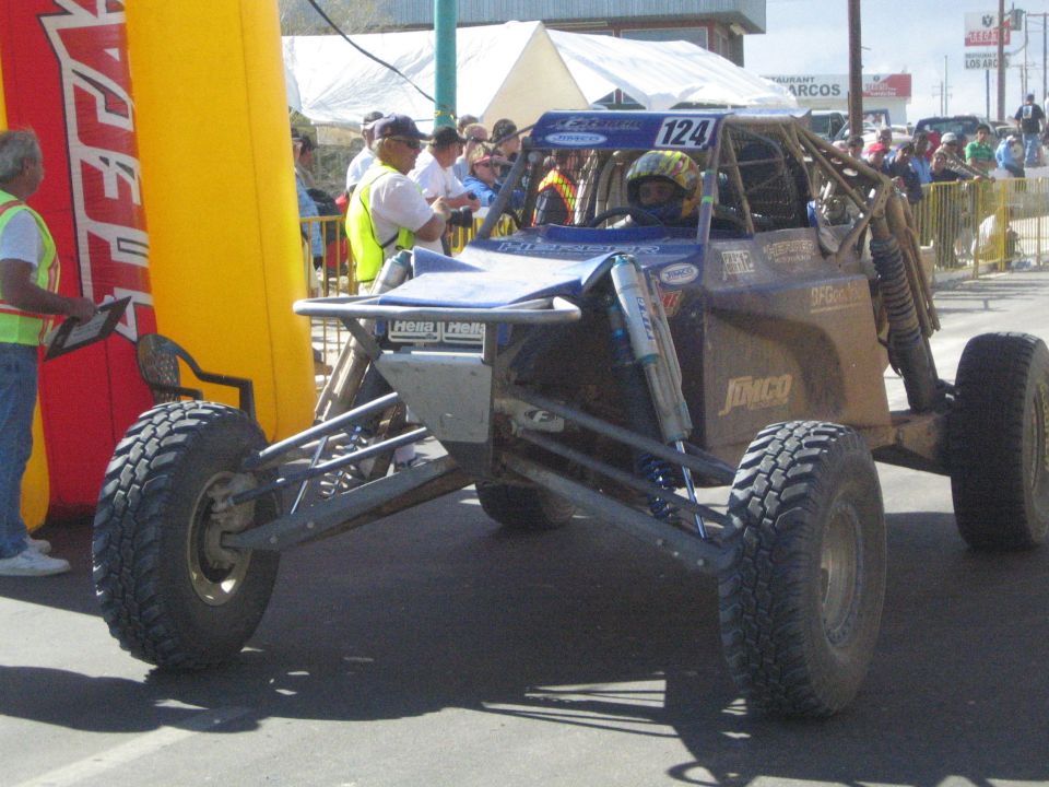 Silver and blue tube-frame race buggy number 124 on pavement
