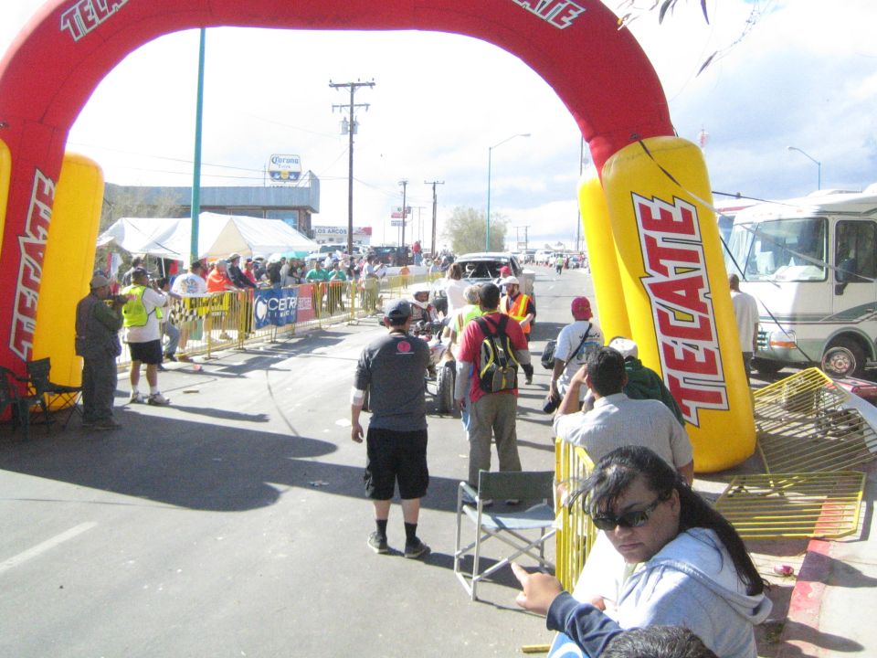 Inflatable red and yellow Tecate arch over a street crowded with spectators
