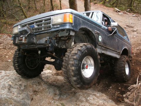 1987 Ford Bronco - A modified 1987 Ford Bronco navigates a rocky trail with its large tires.
