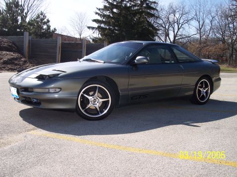 1995 Ford Probe - A dark grey 1995 Ford Probe GTS coupe is shown from the front three-quarter view, aftermarket rims.