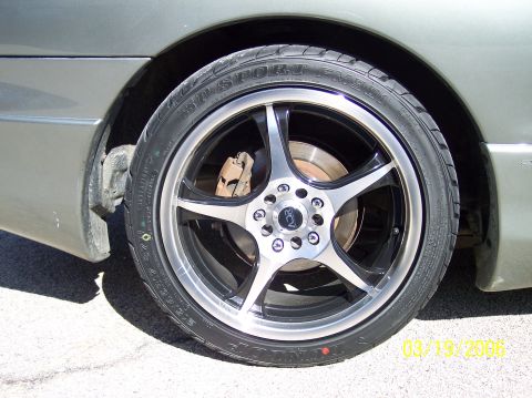 1995 Ford Probe - The wheel features a polished lip and black spokes, with a center cap displaying a stylized logo.