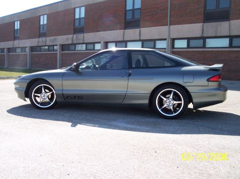 1995 Ford Probe - Side profile of a 1995 Ford Probe GTS coupe with custom wheels parked outdoors.