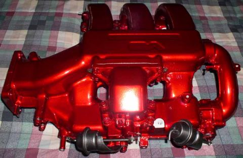 1996 Ford Probe - A shiny red intake manifold with two black vacuum actuators is displayed on a plaid surface.