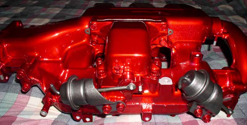 Red metallic intake manifold with two dark gray actuators and visible bolts