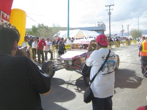 Photographers shooting a white race buggy at a street start area
