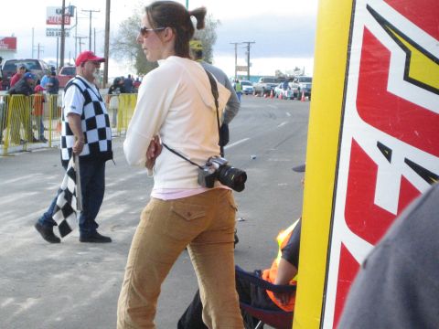 Woman with a DSLR camera and checkered-flag official at a street race