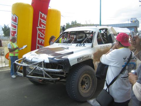 Mud-splattered white off-road race truck number 903 with BFGoodrich branding beside Tecate arch