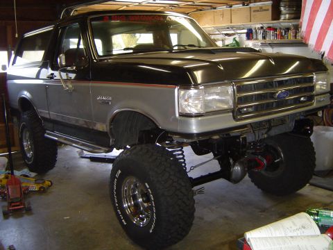 1989 Ford Bronco - This lifted Ford Bronco is in a garage, possibly undergoing modifications or repairs.