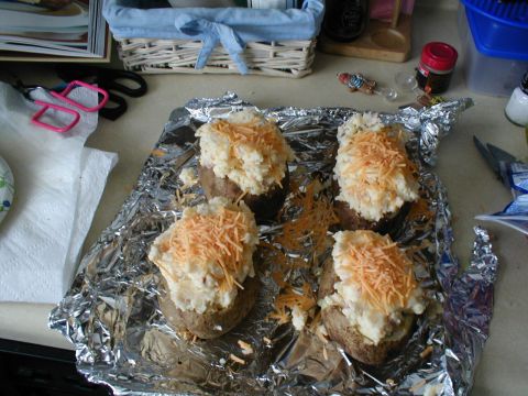 1979 Ford Bronco - Four baked potatoes, topped with a creamy filling and shredded cheese, sit on aluminum foil.