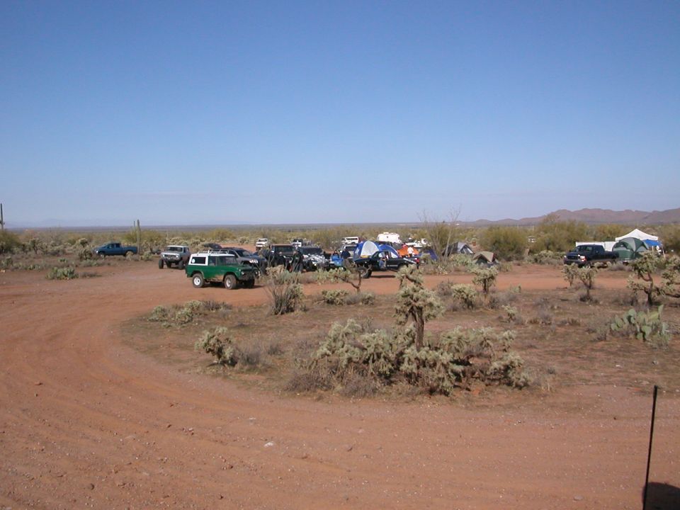 Green 1984 Ford Bronco parked in desert with tents and other vehicles