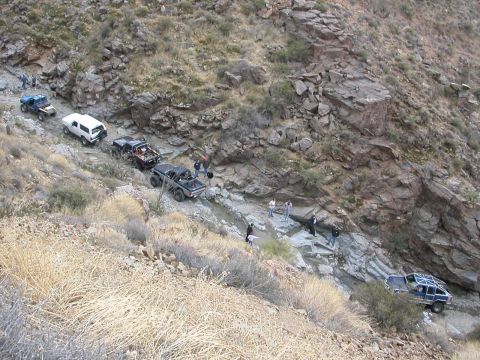 1984 Ford Bronco - Multiple off-road vehicles traverse a challenging, rocky mountain path.