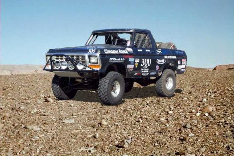 1993 Ford Bronco - This modified Ford truck, likely from the late 1970s, is equipped for off-road racing with a reinforced bumper and numerous sponsor decals.