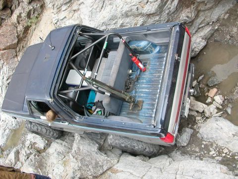 1984 Ford Bronco - This modified vehicle is shown traversing a difficult, rocky path with water and large stones.