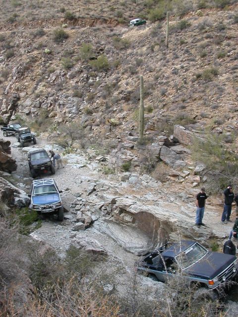 1984 Ford Bronco - A convoy of off-road vehicles makes its way up a challenging, rocky mountain trail.