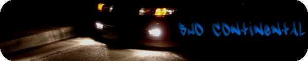 Car with blue graffiti reading "SWD CONTINENTAL" on its side, seen at night from the front