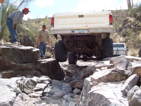 1981 Ford F-150 - A lifted Ford F-Series truck maneuvers through a challenging rocky path, with another white vehicle visible in the background.