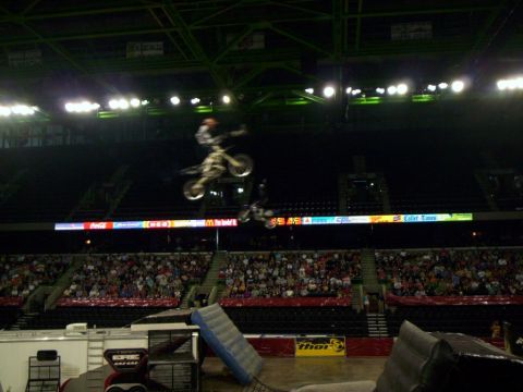 1986 Ford Bronco - Motocross riders perform aerial stunts in a stadium filled with spectators.