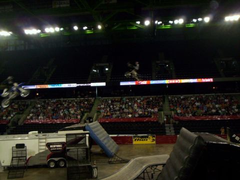 1986 Ford Bronco - Motocross riders perform stunts during an indoor event with spectators in the stands.